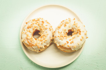 Donat. A plate from donata in white glaze with nuts. Top view. Fresh pastries. Sweet food concept.