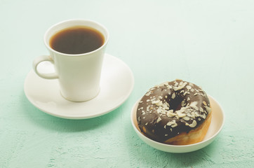 Сoffee break. White cup with black coffee and donat in chocolate glaze.