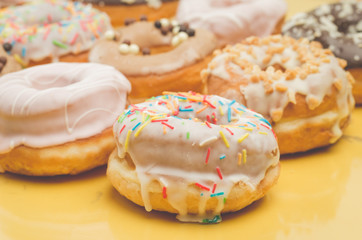 Colorful donut pattern on yellow background. Sweet food concept.