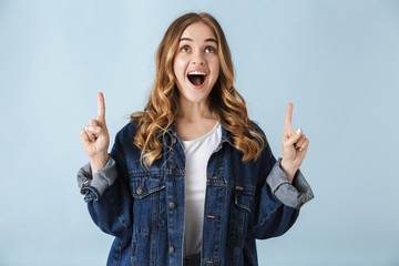 Young excited pretty woman posing isolated over blue wall background pointing.