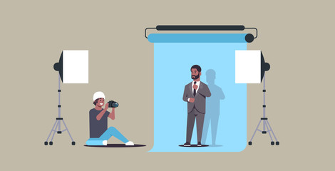 professional photographer using camera shooting business man in formal wear african american model posing in modern photo studio horizontal full length flat