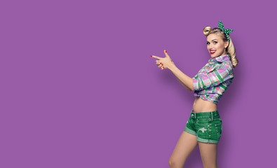 Photo of woman, dressed in pin up style, showing something or copy space, against violet background