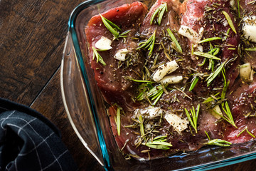 Marinated Raw Tenderloin Meat with Rosemary, Garlic and Olive Oil in Glass Bowl Ready to Cook.