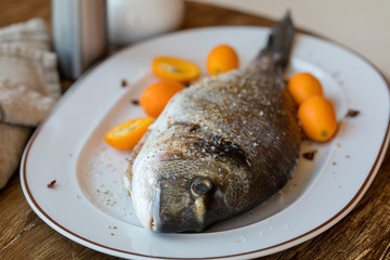 Preparation for roasting in an oven of fresh fish the Gilthead strewed with spices. Soft focus. Easy degradation. Macro.