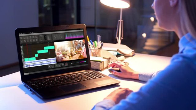 post production, deadline and technology concept - female editor working on video file on laptop computer at night office