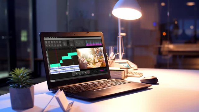 post production, deadline and technology concept - video editor program on laptop computer screen at night office