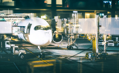 Airplane at terminal gate preparing takeoff by night - Modern international airport with boarding...