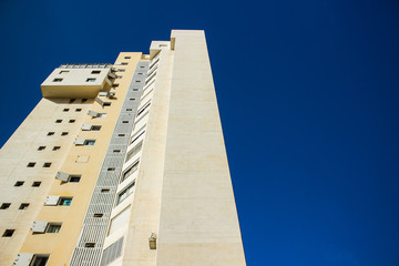 high building tower foreshortening from below on south city street perspective photography on saturated blue sky background with empty copy space for text
