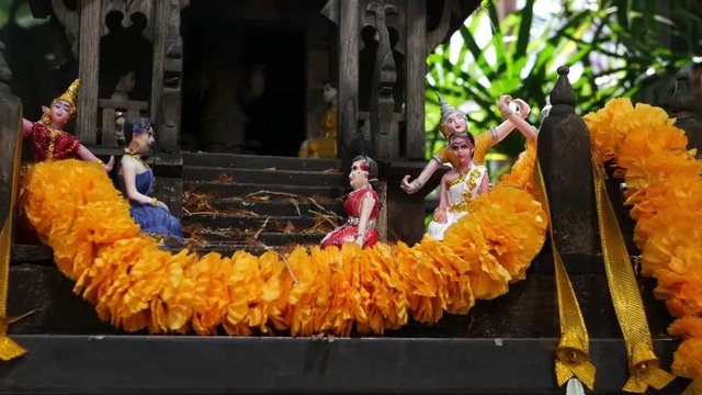 Wooden miniature guardian spirit house. Small buddhist temple shrine, colorful flower garlands. San phra phum erected to bring fortune. Traditional respect animistic rituals, pray ceremonies.