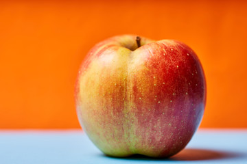 One ripe Apple on an orange-blue background. Macro