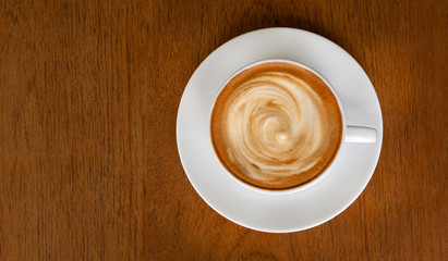 Hot coffee cappuccino latte spiral milk foam top view on wooden background