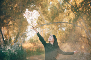 Dreamy beautiful girl with thistle flowers bouquet in golden sunlight on bokeh background with...