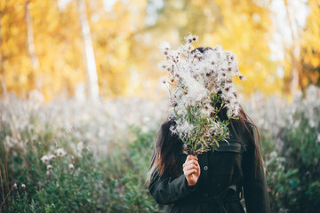 Dreamy beautiful girl on bokeh background of yellow leaves. Inspired girl with white thistle...