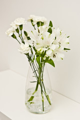 White flowers in glass vase on a shelf