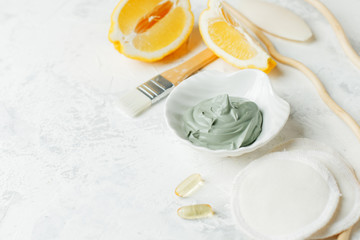 Preparing cosmetic volcanic clay mask with citrus lemon and cosmetic oil on light gray background, concept of natural organic cosmetic products for face body health care