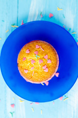 Delicious homemade colorful cupcakes with heart-shaped confectionery close up on a light blue wooden background