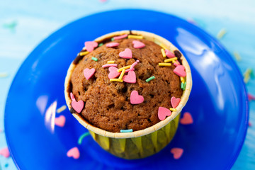 Delicious homemade colorful cupcakes with heart-shaped confectionery close up on a light blue wooden background