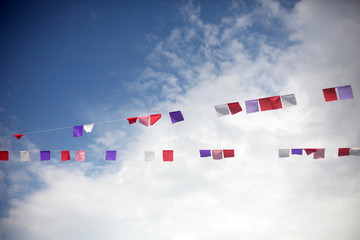 Colorful flags against blue sky with white clouds. Summer celebration concept.