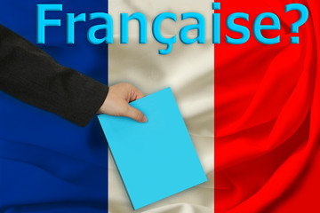 hand of the teacher holds a sheet of paper on the background of the inscription in French "French?" and beautiful flag of France on pleated fabric, copy space
