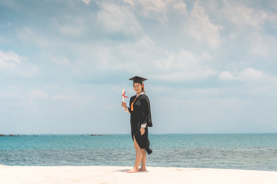 Graduated woman in cap and gown holding certificated celebrating in Commencement day with blue sky on the beach with beautiful sea in summer so proud and happiness,Education Success in summer Concept - Powered by Adobe