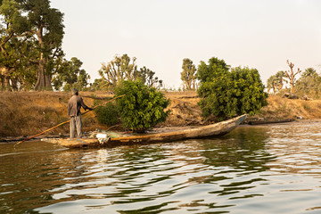 Hombre navegando en barca de madera en Senegal, África.