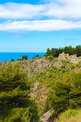 Fototapeta na wymiar Medieval castle ruins Rocca di Cefalu captured on vertical photo with blue Tyrrhenian sea in background. The historical site is located over coastal city Cefalu in Italian Sicily