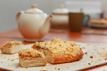 Sweet sand tart with apricot jam. Cut into pieces, lying on a board with a kettle in the background