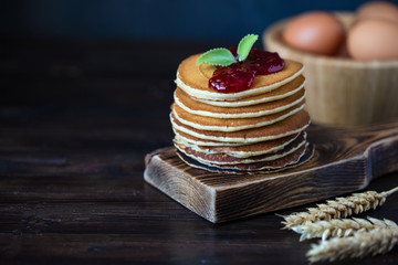 delicious pancakes with jam and mint on a dark wooden table