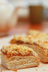 Sweet sand tart with apricot jam. Cut into pieces, lying on a board with a kettle in the background