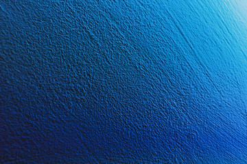 Textured aqua blue painted wall background and texture. The wall is illuminated with cyan light