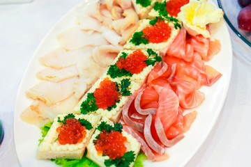 sliced fish and baked basket with red caviar on a plate in a restaurant.