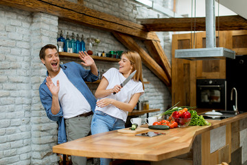 Lovely cheerful couple cooking dinner together and having fun at rustic kitchen