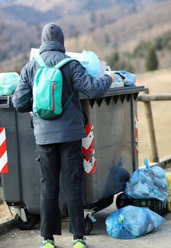 poor boy looks for something to eat in the rubbish bin in winter