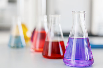 Chemical laboratory flask with blue purple-pink liquid stand on the table