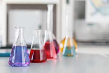 Chemical laboratory flask with blue purple-pink liquid stand on the table