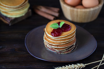 delicious pancakes with jam and mint on a dark wooden table