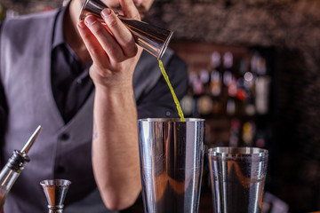 barman preparing cocktai and pours liquid into the jigger in a cocktail bar