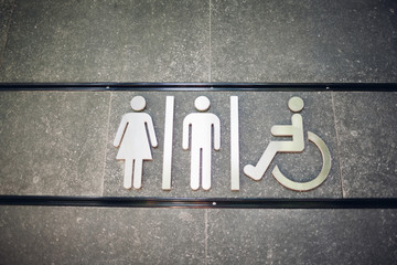 Sign of public toilets WC on wall outdoors. For female, male and disabled people