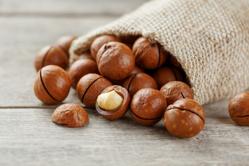 Macadamia nut on a wooden table in a bag, closeup, top view