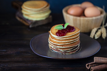 delicious pancakes with jam and mint on a dark wooden table