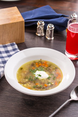 Soup Rassolnik with pickled cucumber and sour cream on wooden table