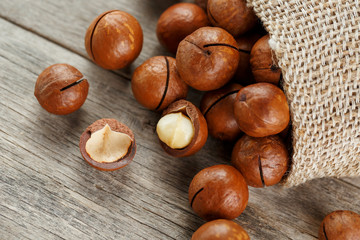 Macadamia nut on a wooden table in a bag, closeup, top view