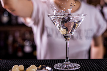 vodka martini isolated on a black background with an olive splashing and air bubbles