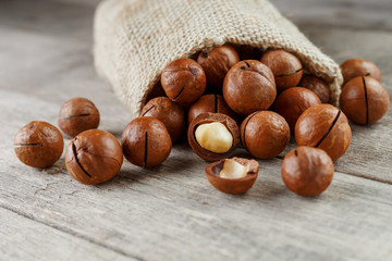 Macadamia nut on a wooden table in a bag, closeup, top view