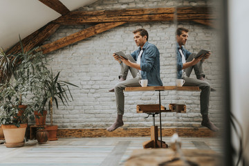 Handsome young man using digital tablet while sitting in the rustic room