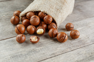 Macadamia nut on a wooden table in a bag, closeup, top view