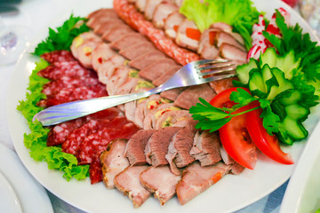 a plate of ham, bacon, salami and sausages. Meat platter.