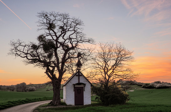 Kapelle mit Bäumen vor dem Sonnenuntergang