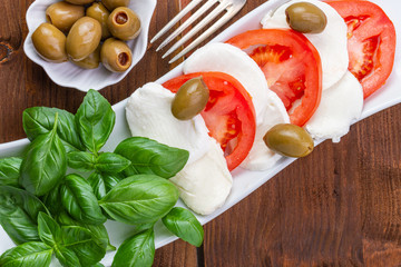 Swieza mozzarella z plastrarmi pomidora i listkami bazyli. Rustykalna kuchnia. Wegetarianskie danie. Vege salatka. © ff25