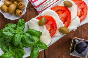 Swieza mozzarella z plastrarmi pomidora i listkami bazyli. Rustykalna kuchnia. Wegetarianskie danie. Vege salatka. © ff25